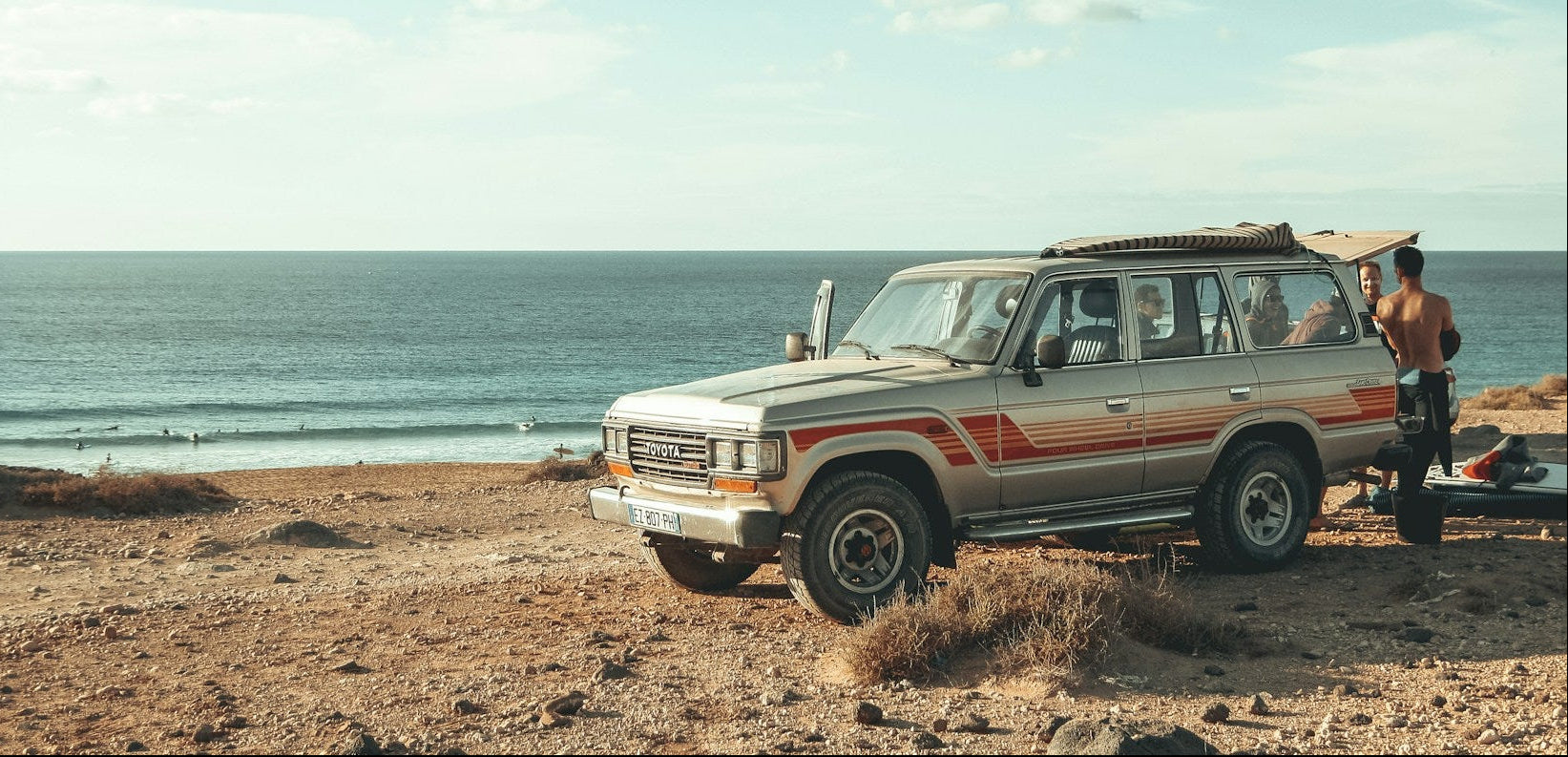 Vintage SUV on a beach with ocean and sky in the background